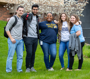 Five students pose for a group photo outside the bookstore on a spring day