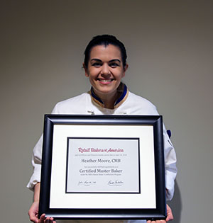 Chef Heather holds her framed certification award with a smile