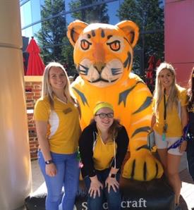 Three female students and Ocelot mascot pose for a group photo