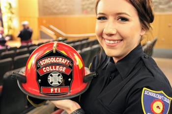 A fire academy graduate posing with a fire hat