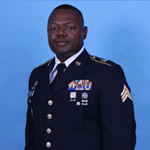 Portrait photo of Timothy Brown II in National Guard uniform with various pins and patches on the dark blue coat.