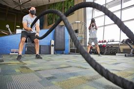 A male wearing a face covering doing ropes at the fitness center