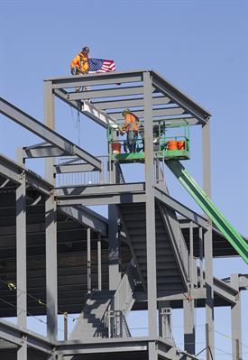 Construction workers place the beam in place up high on the building's beam structure