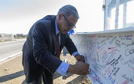 Dr. Jeffress signs building beam that is covered in signatures and notes