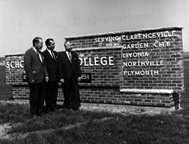 Three men next to Schoolcraft College sign