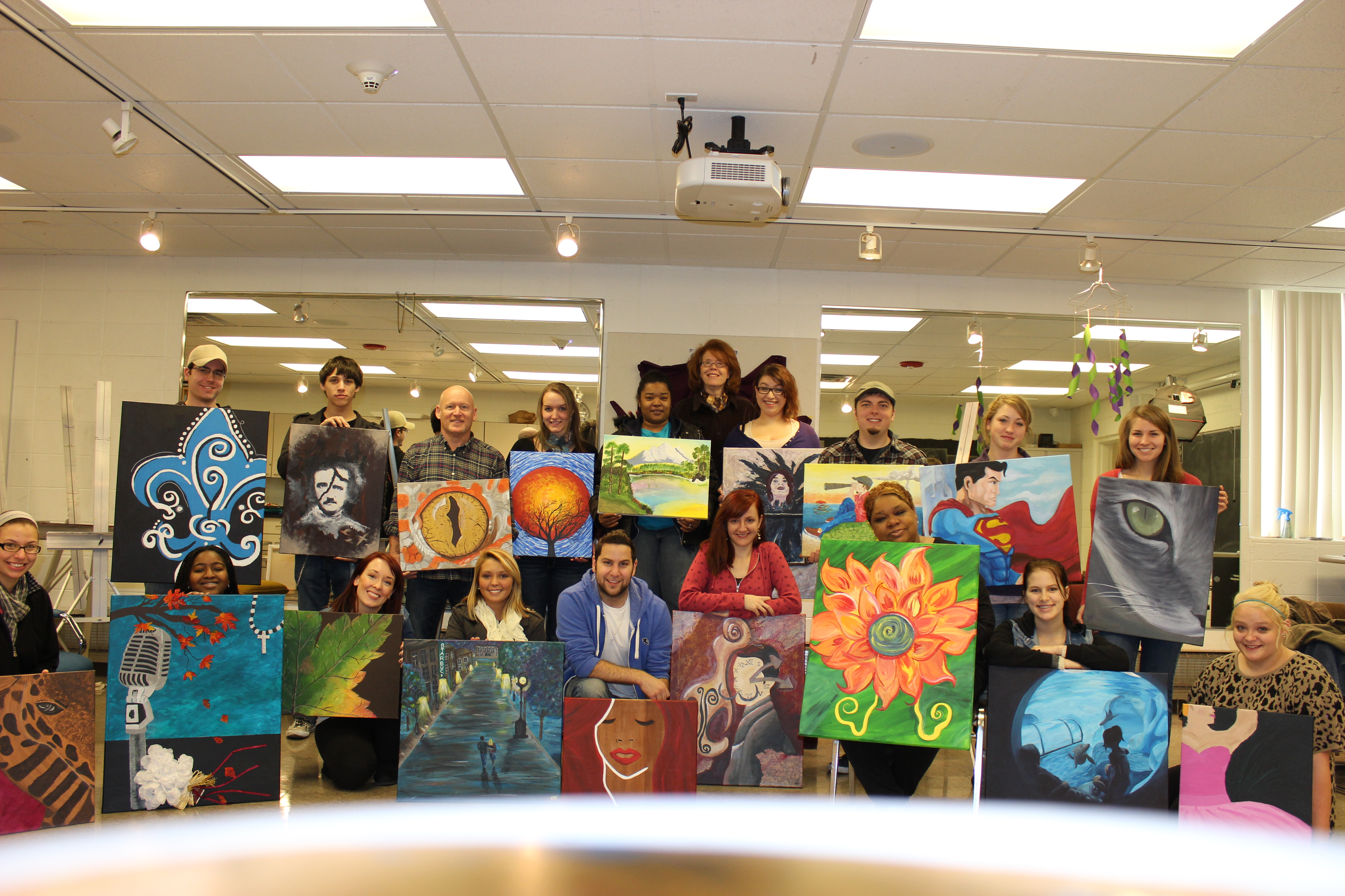 A class of students holding up their paintings