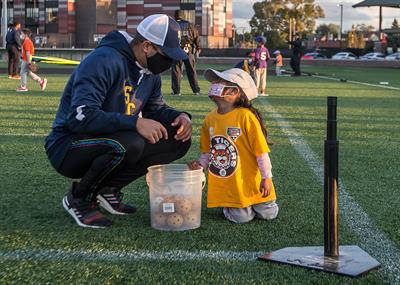 Schoolcraft baseball player talking to a child at eye-level on the field