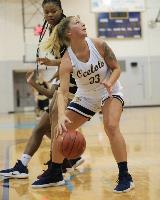 A Schoolcraft player dribbles the ball while looking up at the basket behind her