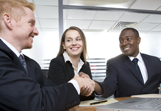 A team business meeting in a corporate setting and two men shake hands